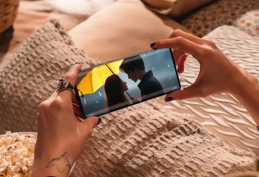 Pessoa segurando um smartphone Motorola Edge 60 Fusion enquanto assiste a um filme romântico.