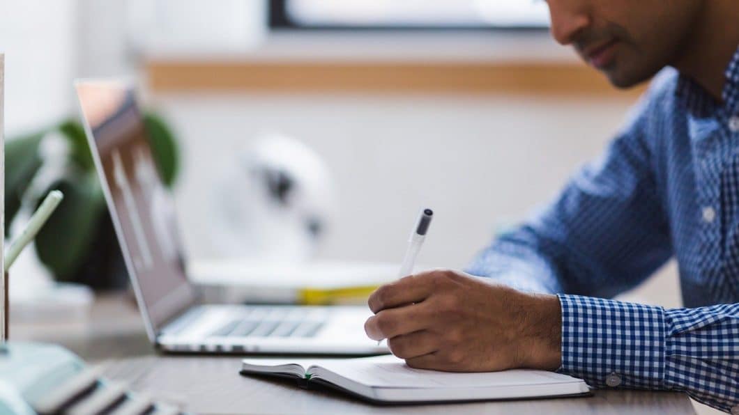 Aluno usando laptop e escrevendo em caderno. Foto: Stocksnap/Pixabay